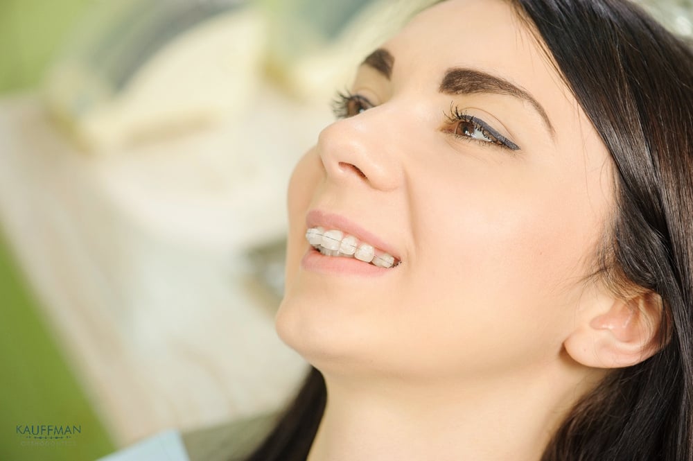 woman with ceramic clear braces on teeth at the dental office - overbite vs underbite in New Braunfels, TX.