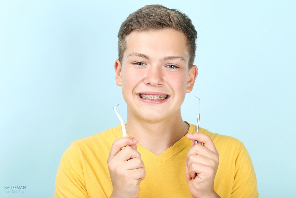 young man with metal braces toothbrush dentist tool - How to Floss with Braces in New Braunfels, TX 