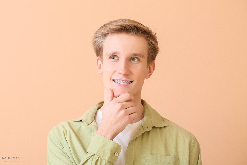 handsome man metal braces color background - Clear Braces vs Metal Braces in New Braunfels, TX